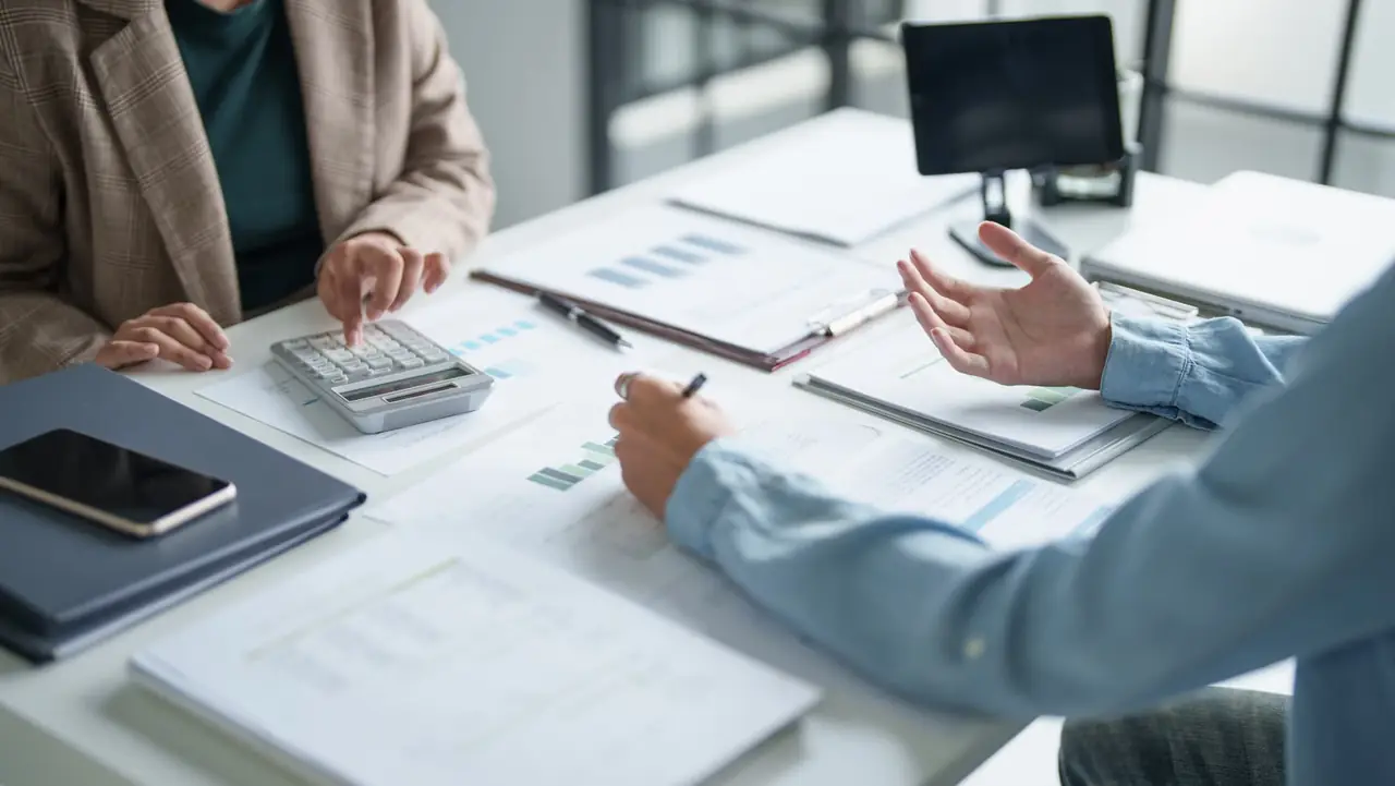 Two professional advisers reviewing financial charts and figures across a meeting table