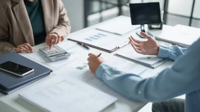 Two professional advisers reviewing financial charts and figures across a meeting table